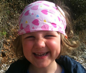 Foto von einem kleinen Mädchen mit bunten Kopftuch und schelmischem Lachen